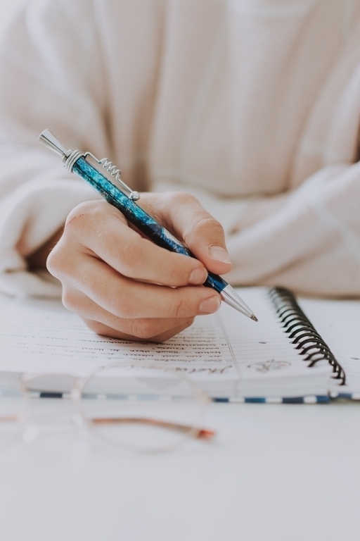 vertical-selective-closeup-female-writing-notebook-with-blue-pen